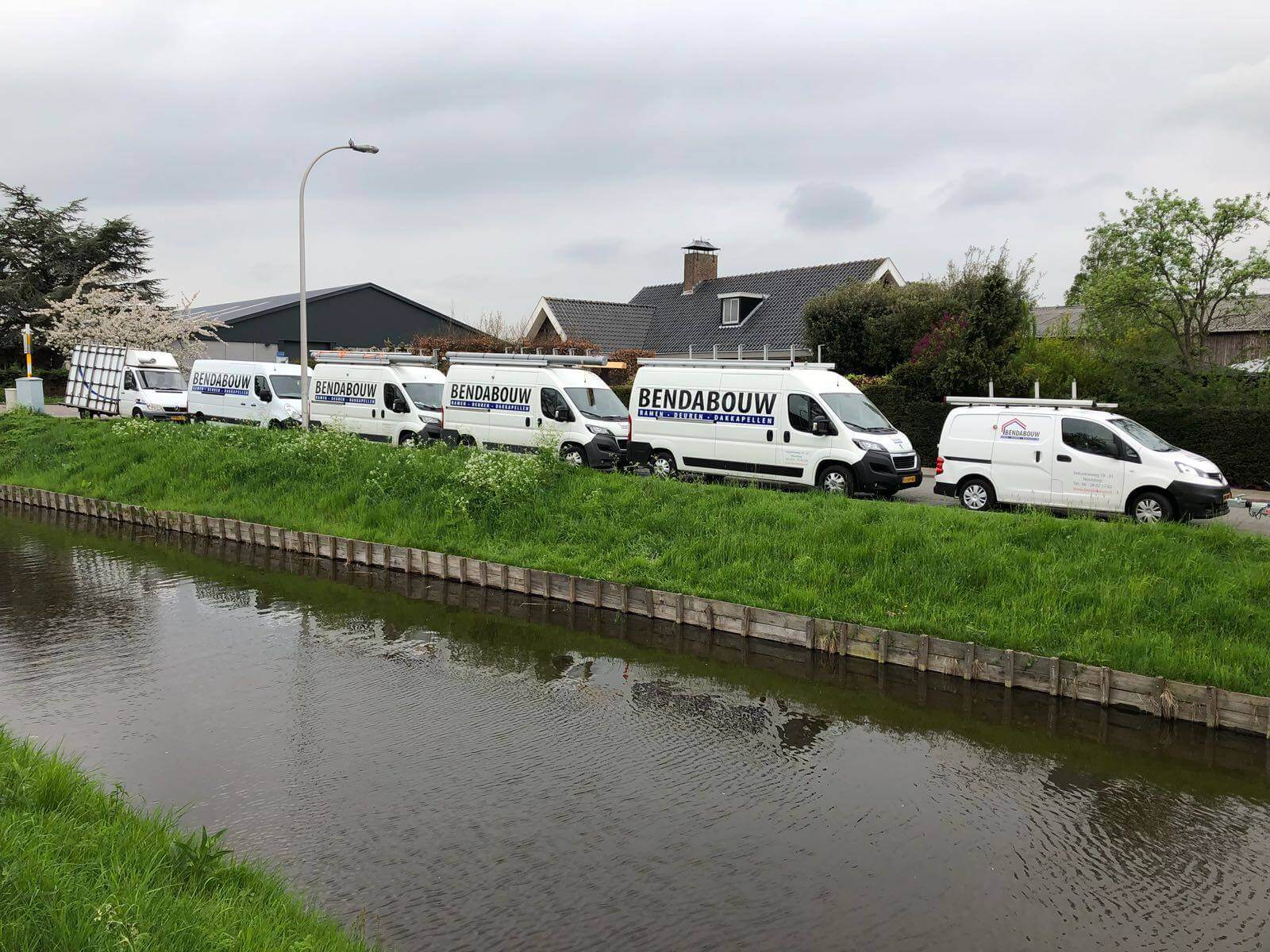 Rij witte bedrijfsbussen van Bendabouw