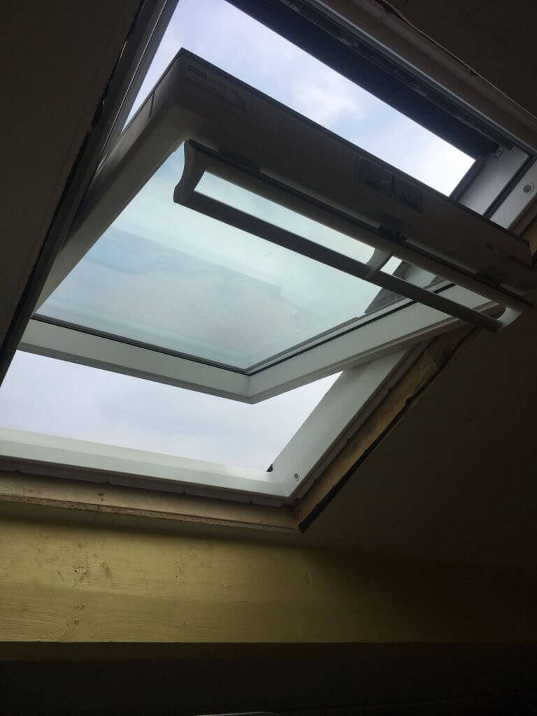 Geopend wit dakraam van binnenuit gezien tijdens montage, met zicht op de lucht
